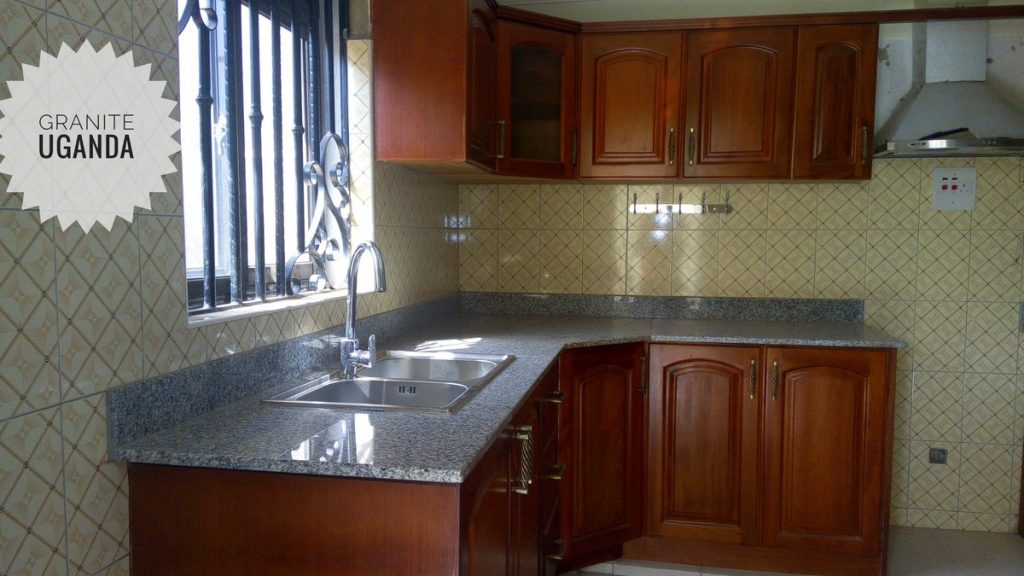 a granite kitchen counter with wooden kitchen cabinets